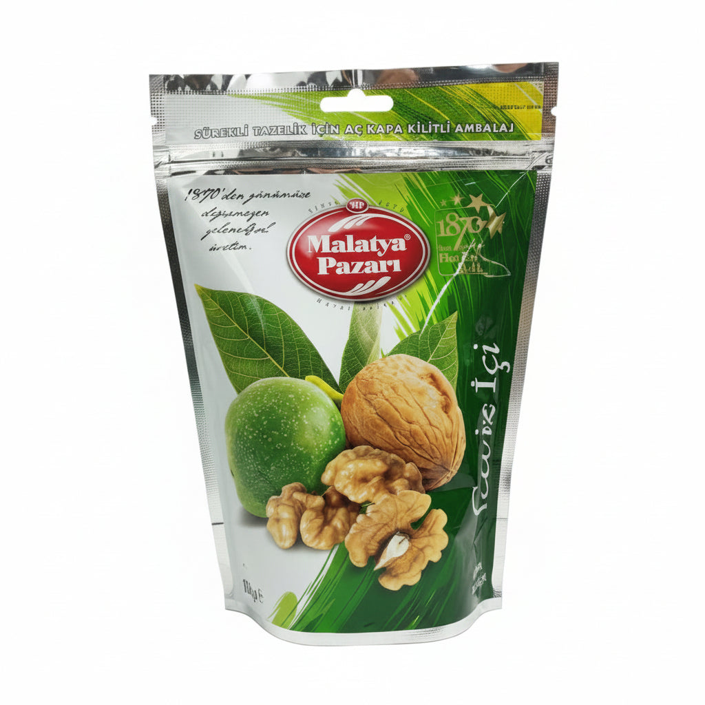 A stand-up pouch of Malatya Pazarı walnut spread on a wooden tabletop, with a busy indoor background including cardboard boxes and shelving.
